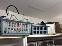 Two small gray plastic baskets on a shelf containing purses and a white satin ring pillow in the background.