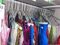 Several sarees hanging on a rack showing variety of colors and textures including silky and patterned sarees.