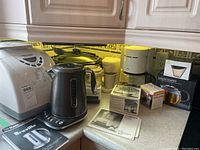 Full view of all appliances on kitchen counter including Black & Decker bread maker, Breville kettle, Braun coffee maker, and Bodum Assam teapot box.