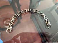Full view of the linked bracelet arranged curved, showing overall design and clasp ends.