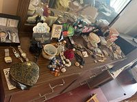 Wide shot showing entire collection of watches, jewelry, boxes, and music box arranged on wooden dresser top.