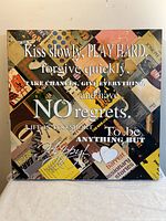 Front view of a square wooden wall art piece with a colorful collage background and a large inspirational quote printed over it.