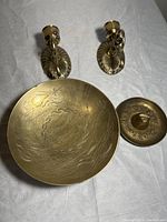 Photo of two brass wall candle holders and an engraved brass dish with dragon design and a brass ashtray