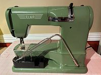 Front profile of green Elna Supermatic with knee lever and accessory tray attached