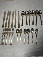 All flatware pieces arranged on a surface: top row 6 knives, 6 large spoons; bottom row 5 forks, 6 teaspoons.