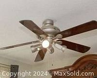 Ceiling fan installed on residential ceiling featuring five wooden blades and light fixture.
