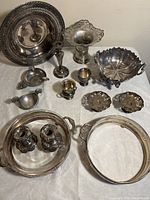 Top down view showing entire collection of silver and pewter items arranged on white cloth background