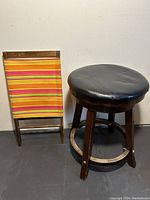Photo of beach folding chair beside rotating bar stool under neutral lighting.