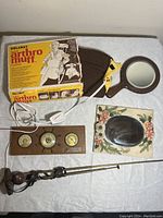 Complete lot including Solaray arthro muff in box, wooden barometer, two mirrors, and indoor antenna on white surface.
