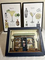 Two framed cocktail-themed recipe art prints and one framed 3D bake shop wall art arranged together, showing overall lot contents and size.