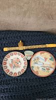 Full view of plates, teacup and decorative pipe showing overall design and colors
