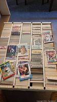 Top-down view of divided box filled with sports cards organized in labeled sections.