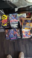 Six sealed boxes of NBA trading cards arranged on floor near furniture.