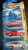 Three Hot Wheels cars in original 2008 New Models packaging, including an orange and red car with detailed paint and wheels.