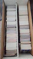 Box of stacked loose singles trading cards separated by cardboard divider