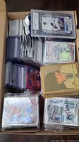 Full box view of assorted sleeved and top-loaded sports cards