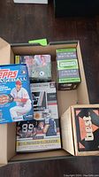 Opened box view containing multiple trading card boxes and loose cards including 2012 Topps Baseball, Donruss football, and 1990 Best set box