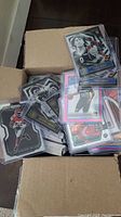 Open cardboard box filled with sleeved sports trading cards