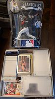 Various sports cards stacked inside open box, showing card designs and protective sleeves.