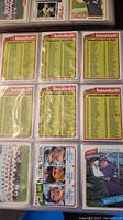 Photo of multiple Topps baseball checklist cards arranged in binder sleeves covering numbers 1-726 in sections, with some player cards including Alan Bannister.