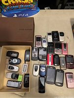 Top view of vintage mobile phones spread and arranged on table and in box, showing Samsung and LG flip phones, candybar and slider types.