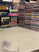 Overall view of the stacked CDs and audio books showing multiple titles and spines.