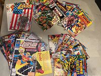 Multiple comic books spread out showing covers including The Thing, Daredevil, Quasar, Ghost Rider, Superman, and LoBo.