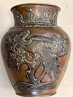 Front view showing one side of the bronze vase with a raised phoenix design perched on floral branches.