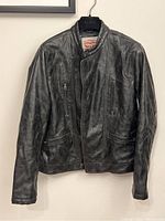 Front view of the Levi Strauss & Co black leather jacket, showing the zippered chest pockets and zipper closure.