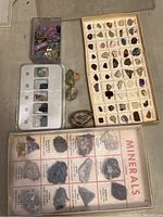 Top down photo showing two display boxes filled with mineral and rock samples, several loose specimens around them, and a mineral identification chart laid flat.