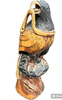 Side view of the carved wooden parrot holding a snake, showing detailed paint and carving.