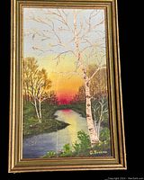 Framed oil painting on board showing a river landscape at sunset with birch trees and signed by G. Brochu.