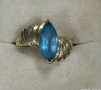 Top view showing marquise-shaped blue topaz in gold prong setting and decorative gallery