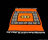 Full view of vintage heavy wool blanket rug with orange center and fringed edges.