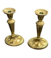 Two small vintage brass candle holders photographed from front and side angle on white background