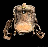 Front view of vintage brown leather children's western saddle showing seat, tooling, horn, and stirrups
