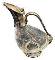 Decanter pitcher shaped like a duck or goose with silver-plated handle, spout, and base, photographed from a side angle.