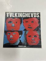 Front cover of Talking Heads 'Remain In Light' vinyl record sleeve showing band member faces with red paint overlay.