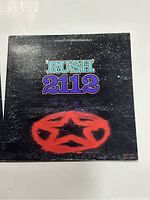 Front cover of Rush 2112 vinyl album showing title and red star emblem on black background.