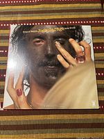 Front cover of Frank Zappa Joe's Garage Acts II & III vinyl record showing colorful close-up portrait with black face paint and red fingernails.