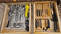 Drawer with organized flatware including forks, spoons, and knives along with a lemon squeezer.