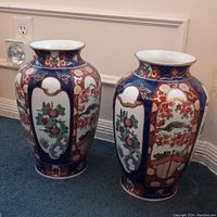 Pair of vintage Japanese Imari vases placed on carpeted floor with visible floral and geometric designs in blue, red, and gold.
