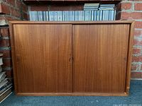 Front view of cabinet with closed sliding doors and CDs on top