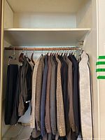 Photo showing 9 jackets in shades of brown, blue, and checked patterns on wooden hangers in closet.