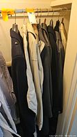 Photo showing five men's winter coats hanging on a rod in assorted colors including navy, beige, black, gray, and tan.