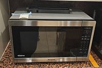 Front view of the Panasonic microwave showing the stainless steel finish, door with dark glass, and control panel on the right side.