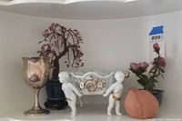 Photo showing overall lot with sterling silver goblet, porcelain candy dish with cherubs, and stone flower decorations.