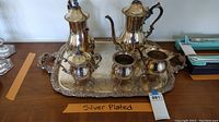 Full view of the entire silver-plated coffee service set on the ornate tray, showing all items grouped together.