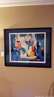Frontal photo of framed colorful abstract musician themed art print on beige wall.