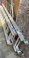 Photo showing several aluminum ladders stacked together, including the one for sale.